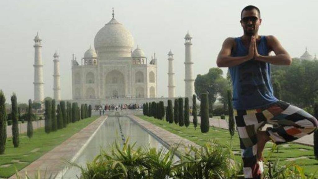 Άνδρας σε στάση yoga μπροστά από το διάσημο κτίριο της Ινδίας το Taj Mahal