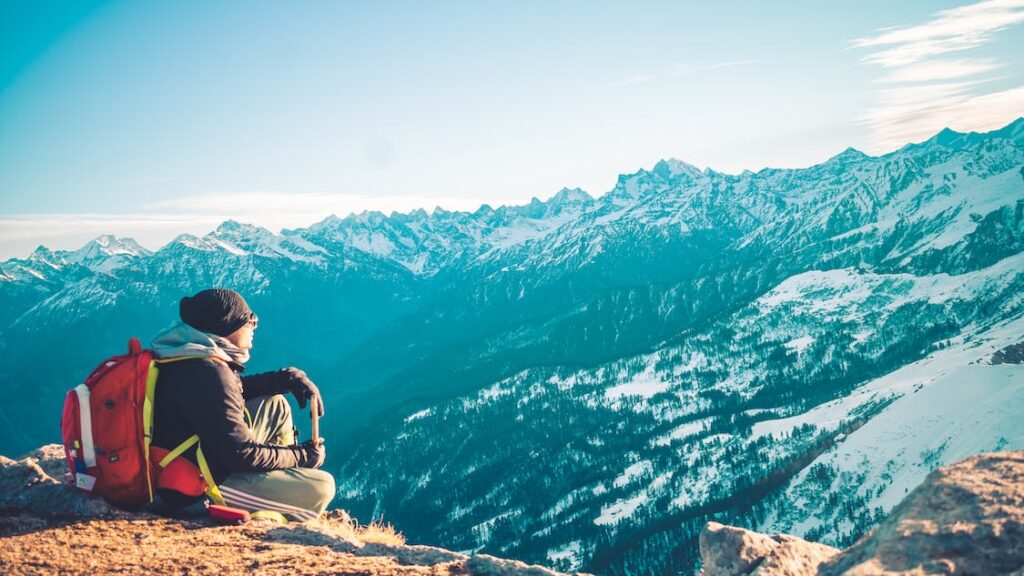 Μια κοπέλα σε καθισμένη κοιτάζοντας τη χιονισμένη θέα των βουνών