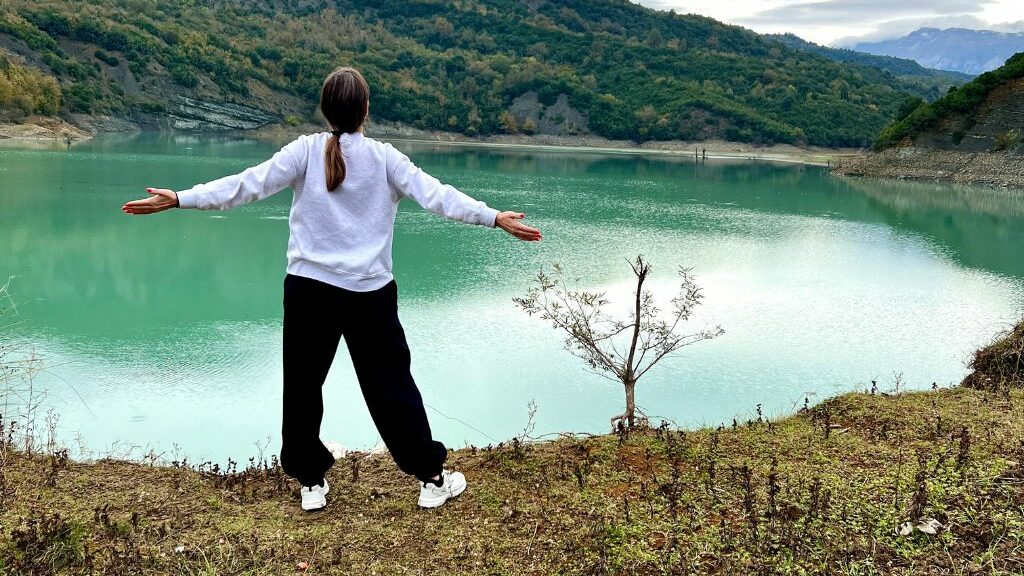 Κοπέλα που ανοίγει τα χέρια της μπροστά σε μια λίμνη