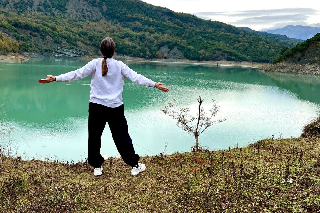 Κοπέλα που ανοίγει τα χέρια της μπροστά σε μια λίμνη