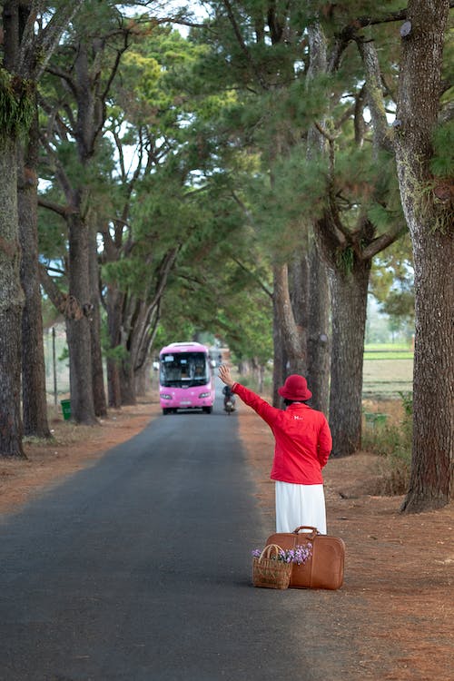 Κοπέλα που βγάζει το χέρι της σε δρόμο για να σταματήσει ένα λεωφορείο