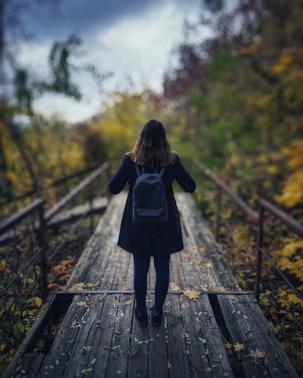 Κοπέλα που περπατάει πάνω σε ξύλινο διάδρομο μέσα στη φύση