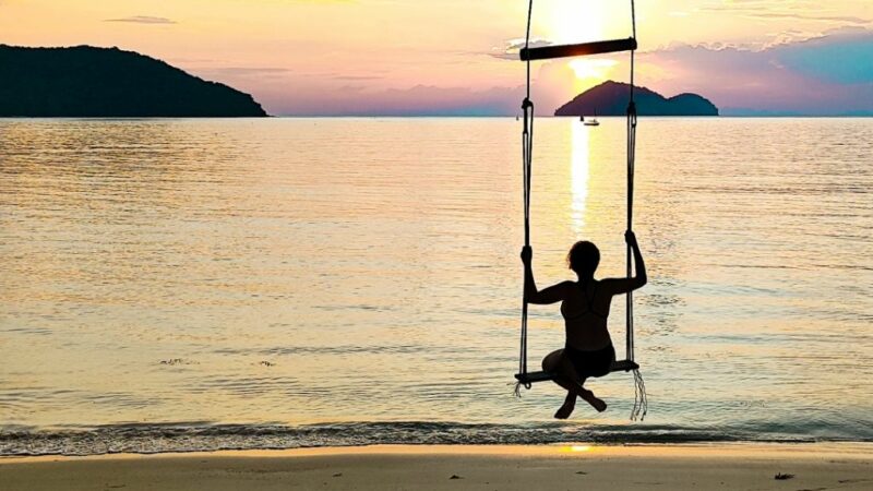 Κοπέλα που κάνει κούνια με μαγιό σε μια παραλία την ώρα του ηλιοβασιλέματος