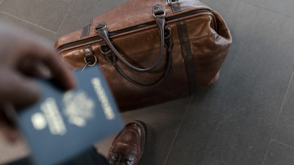 Καφέ βαλίτσα και διαβατήριο στο χέρι