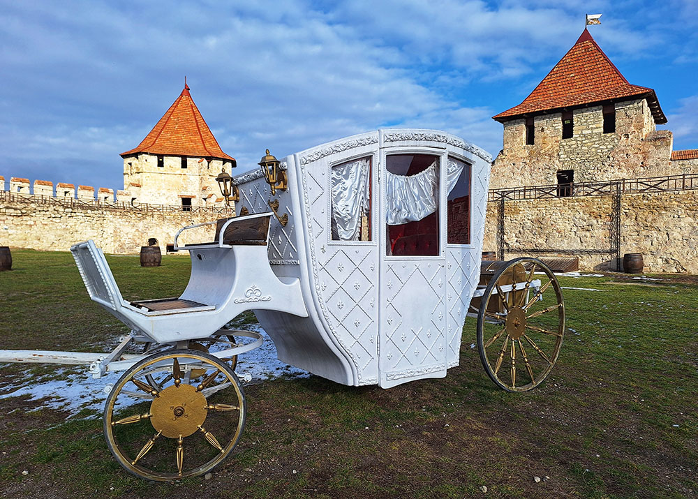Λευκή άμαξα στο γρασίδι και πίσω ένα πετρόχτιστο κάστρο 