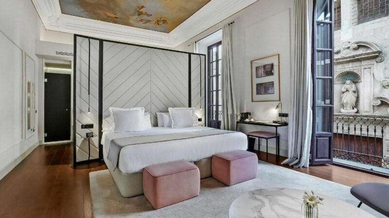 Δωμάτιο ξενοδοχείου με διπλό κρεβάτι με λευκά σεντόνια, ζωγραφισμένη οροφή και μικρό μπαλκόνι