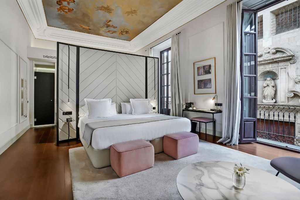 Δωμάτιο ξενοδοχείου με διπλό κρεβάτι με λευκά σεντόνια, ζωγραφισμένη οροφή και μικρό μπαλκόνι