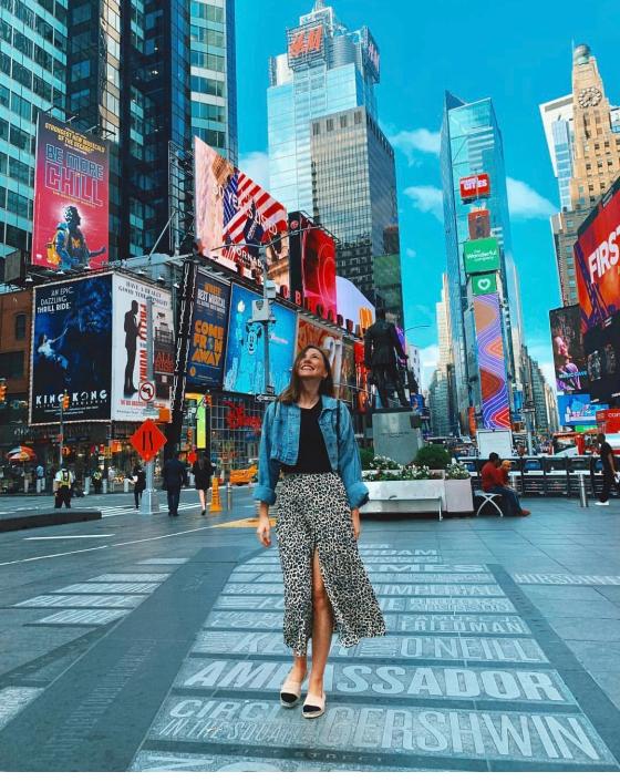 Κοπέλα που περπατάει στη Νέα Υόρκη με πολλά κτίρια πίσω της