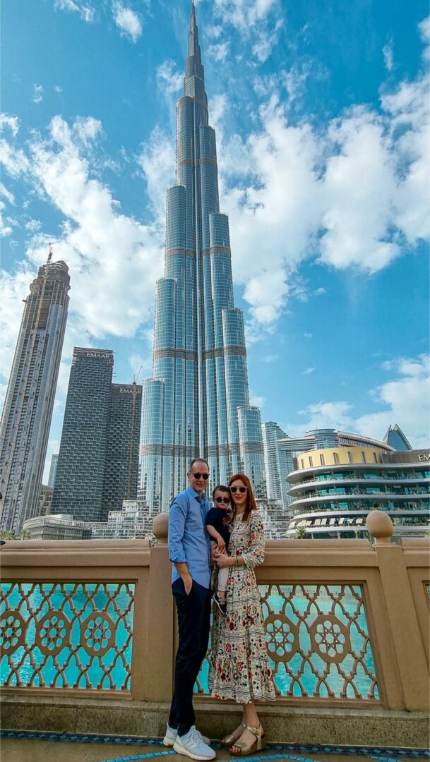 Οικογένεια με ένα παιδάκι στα χέρια, φωτογραφίζεται μπροστά από ένα τεράστιο κτίριο στο Ντουμπάϊ