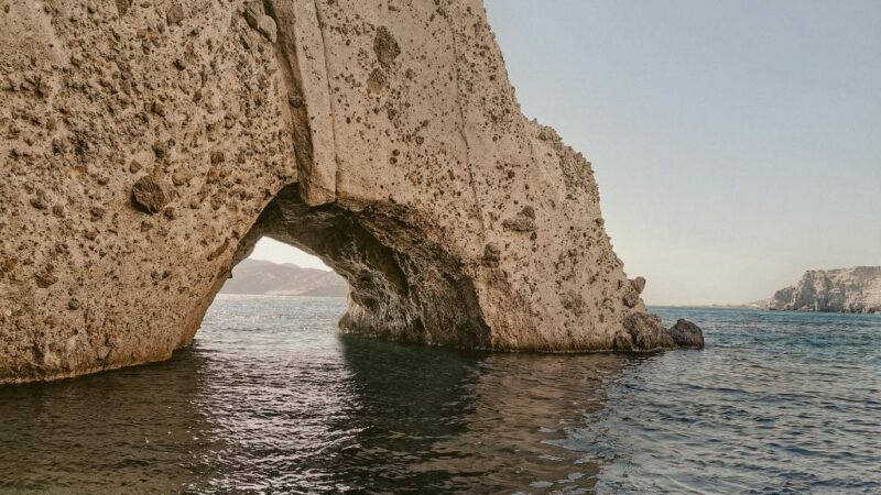 Βράχος με τοξωτό άνοιγμα που περνάει νερό ανάμεσα, μέσα στη θάλασσα