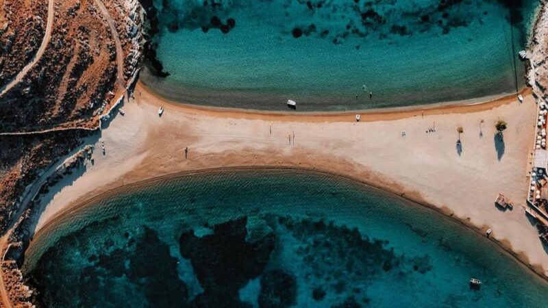 Φωτογραφία από ψηλά της παραλίας Κολώνας που χωρίζεται από μια λωρίδα άμμου και προκύπτουν δύο παραλίες με γαλάζια νερά